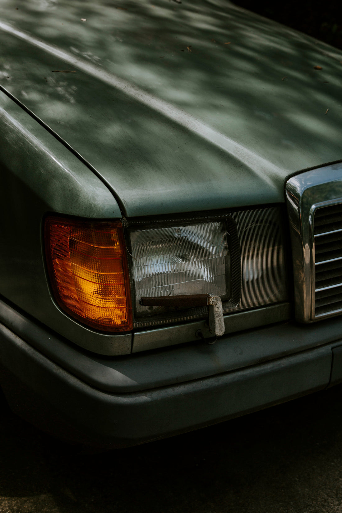 Frontscheinwerfer eines dunkelgrünen Autos